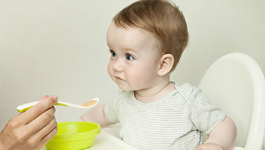Child in high chair being spoon fed.