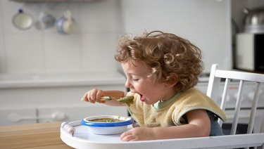 Toddler boy feeding himself