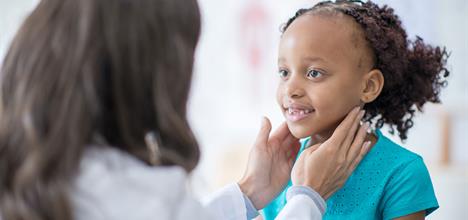 A doctor examines a young girl, smiling in a medical setting.